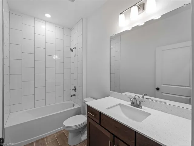 Full bathroom featuring wood finish floors, toilet, shower / bath combination, and vanity