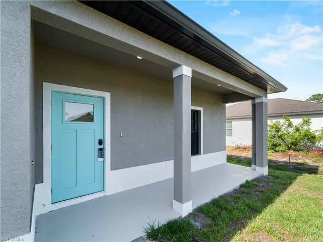View of exterior entry with stucco siding and a patio area