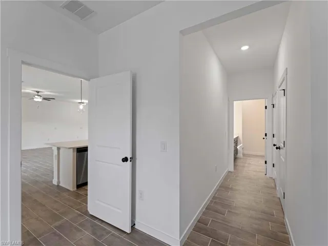 Hallway featuring wood tiled floors, baseboards, and recessed lighting