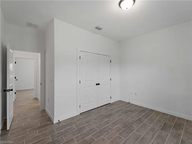 Unfurnished bedroom featuring wood finish floors, baseboards, and a closet
