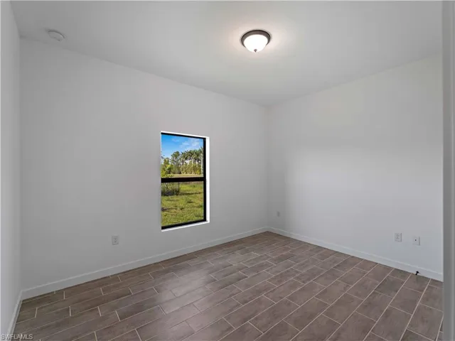 Spare room with wood tiled floors, baseboards, and a smoke detector