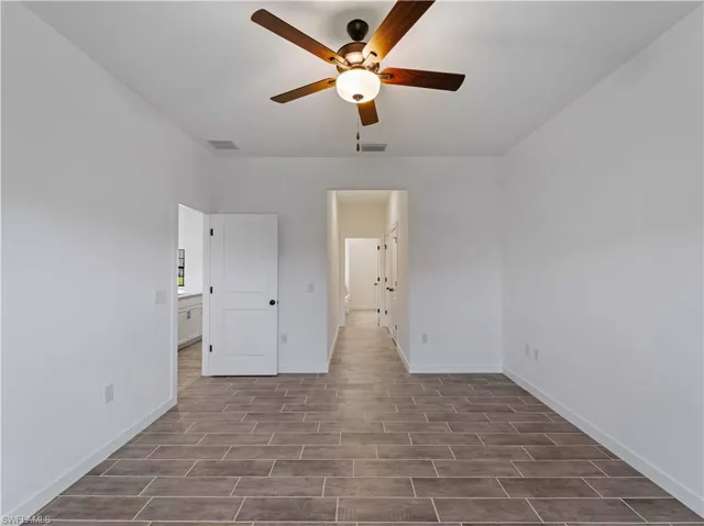 Unfurnished bedroom featuring wood finished floors, baseboards, and a ceiling fan