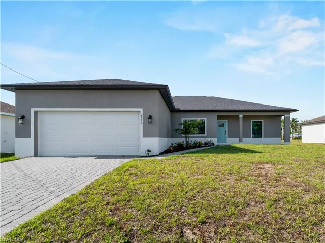Ranch-style house with a garage, decorative driveway, stucco siding, and a front lawn