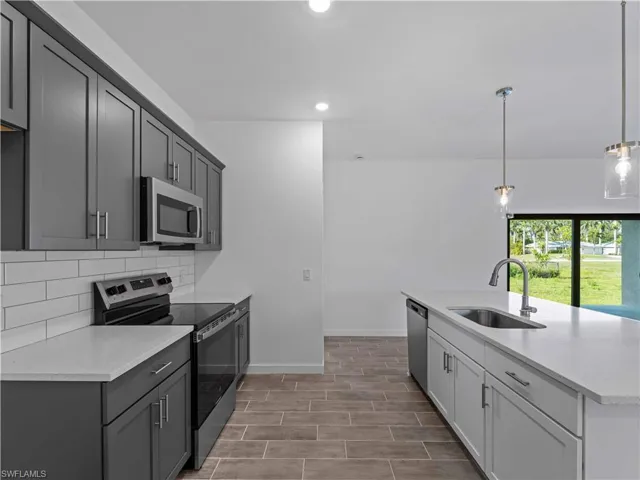 Kitchen featuring appliances with stainless steel finishes, a sink, recessed lighting, tasteful backsplash, and light countertops