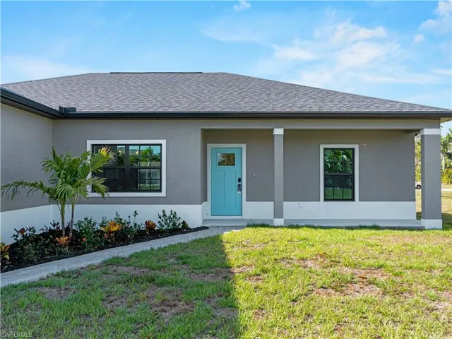 View of front of home with a front lawn, roof with shingles, and stucco siding