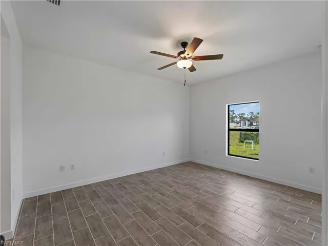 Unfurnished room with ceiling fan, dark wood-type flooring, and baseboards