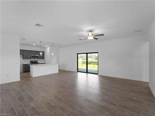 Unfurnished living room featuring ceiling fan, recessed lighting, baseboards, and dark wood finished floors