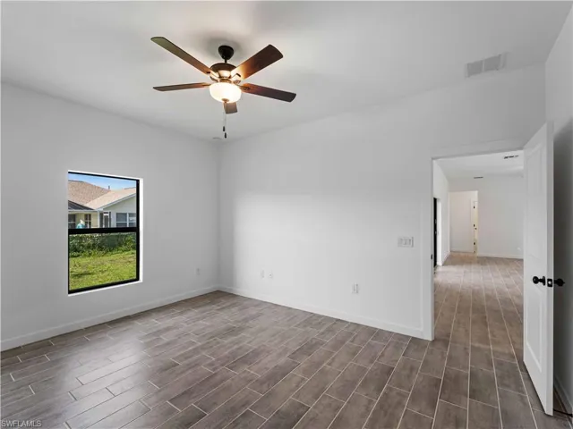 Unfurnished room with dark wood-style floors, a ceiling fan, and baseboards