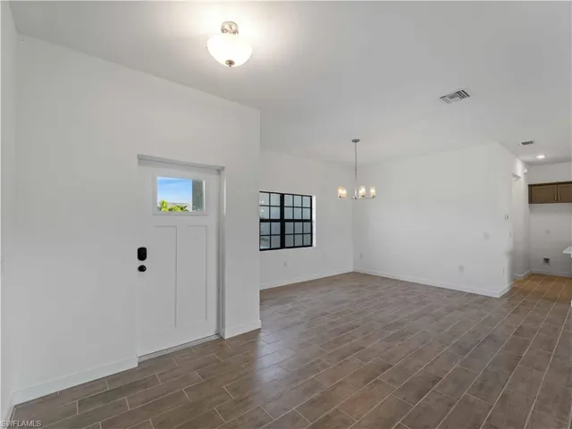 Foyer with a chandelier, dark wood finished floors, and baseboards