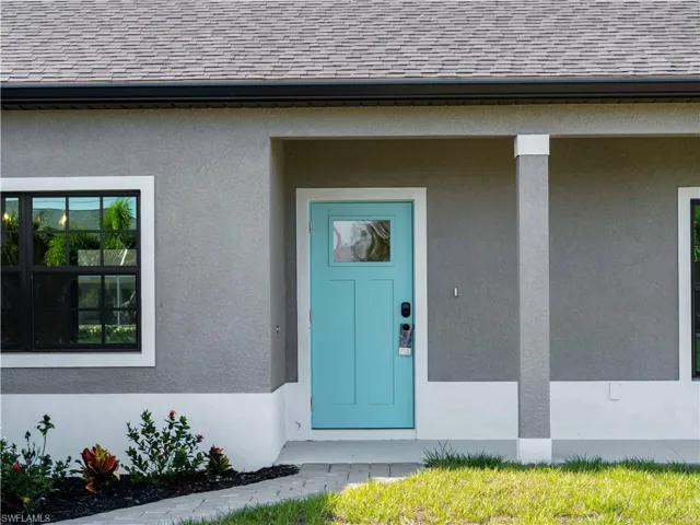 Entrance to property featuring roof with shingles and stucco siding