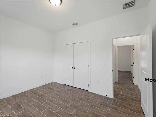 Unfurnished bedroom with wood finish floors, baseboards, and a closet