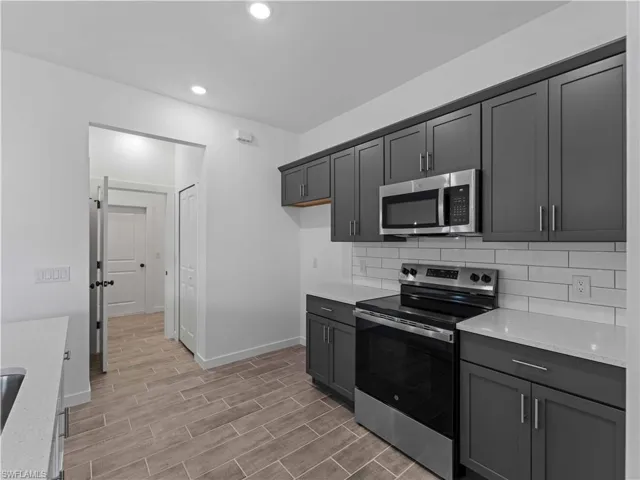 Kitchen with stainless steel appliances, baseboards, backsplash, light wood finished floors, and recessed lighting