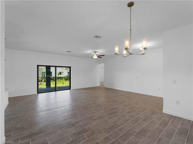 Empty room with a chandelier, baseboards, dark wood finished floors, and a ceiling fan