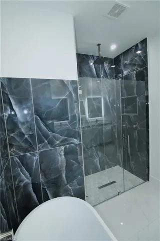 Bathroom featuring tile walls and separate shower and tub