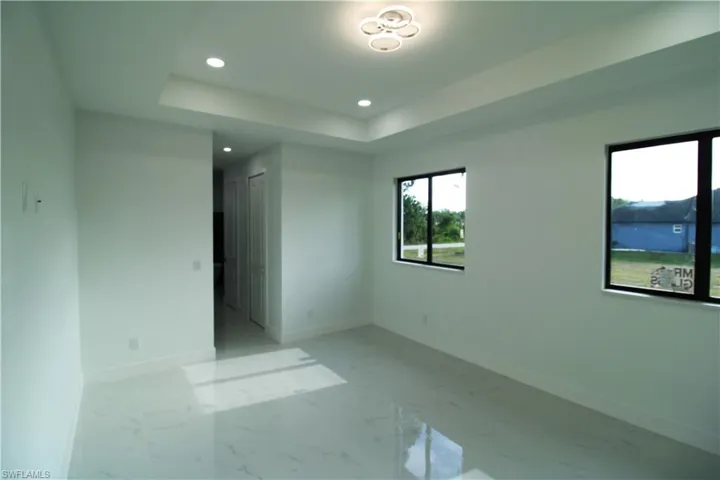 Tiled empty room featuring a tray ceiling