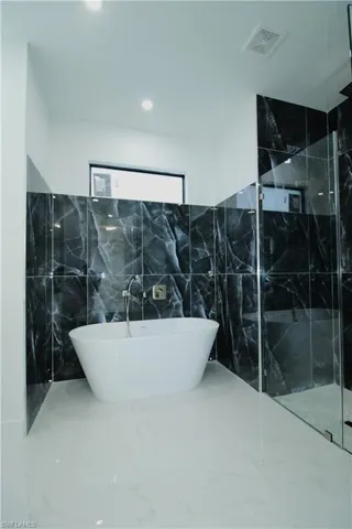 Bathroom featuring tile walls, tile floors, and plus walk in shower