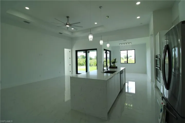 Kitchen with a healthy amount of sunlight, black fridge, sink, and a tray ceiling