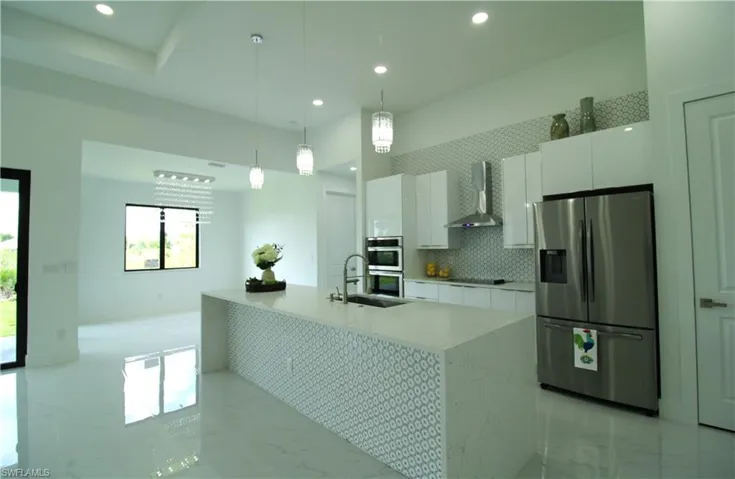 Kitchen featuring stainless steel appliances, white cabinets, light tile floors, and wall chimney exhaust hood