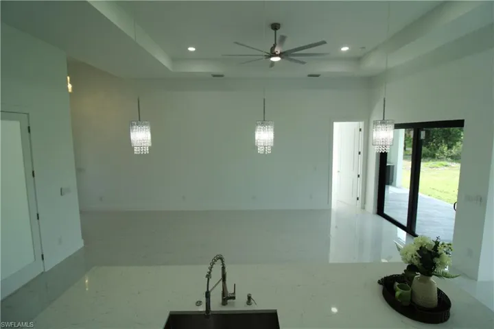 Kitchen with a tray ceiling, pendant lighting, a towering ceiling, sink, and ceiling fan