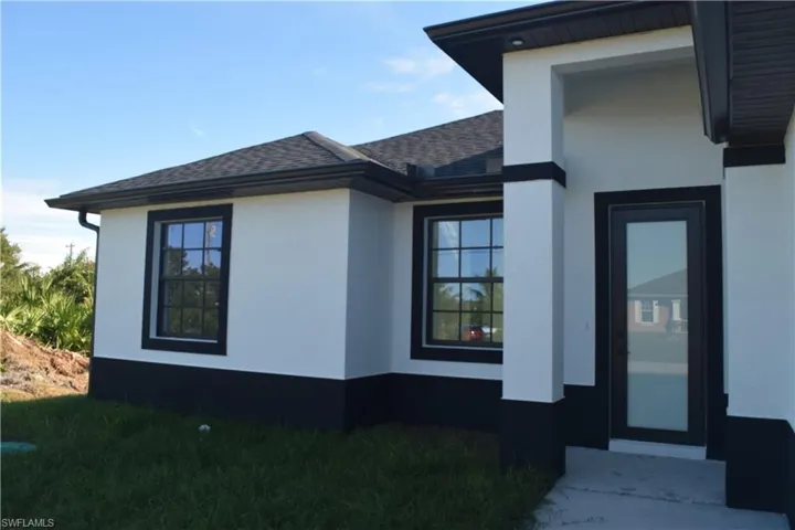 View of property exterior with roof with shingles, stucco siding, and a yard