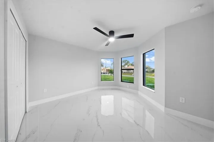 Unfurnished bedroom featuring marble finish flooring, ceiling fan, and a closet