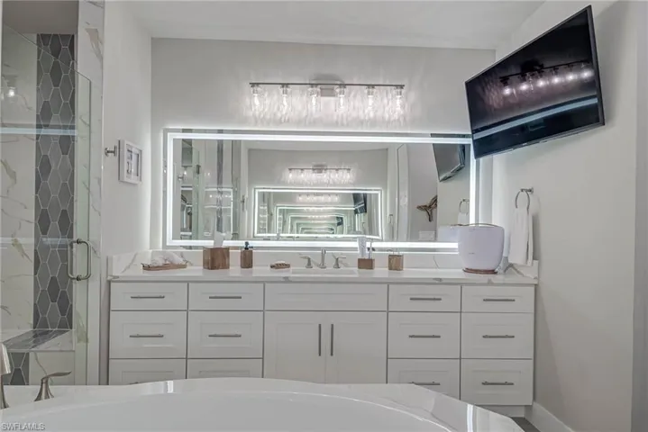 Full bathroom featuring vanity, a marble finish shower, and a bathtub
