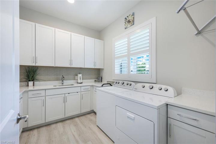 Laundry area with ample cabinetry and sink.