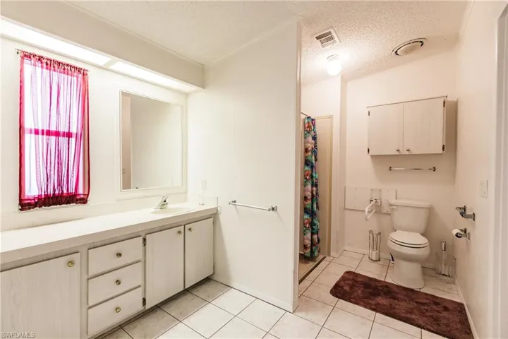 Bathroom featuring toilet, tile patterned flooring, crown molding, vanity, and a textured ceiling
