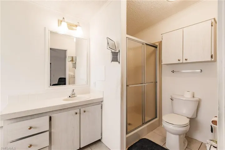 Bathroom with tile patterned floors, toilet, a shower with door, and vanity