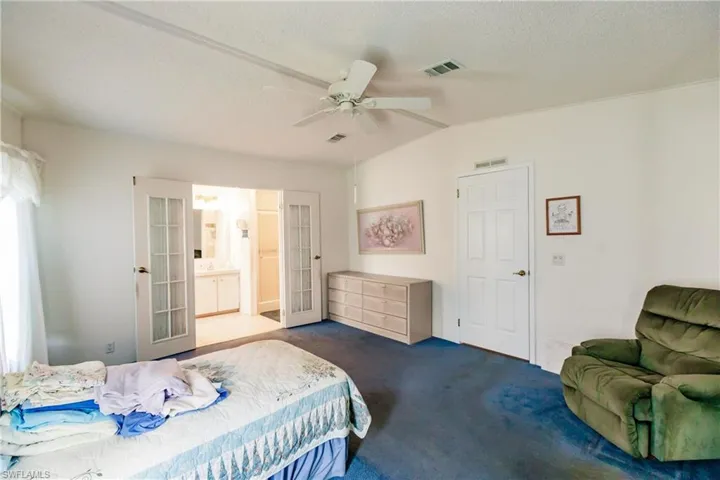 Bedroom with a textured ceiling, connected bathroom, ceiling fan, french doors, and lofted ceiling