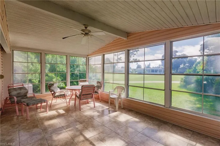 Unfurnished sunroom featuring ceiling fan and vaulted ceiling with beams
