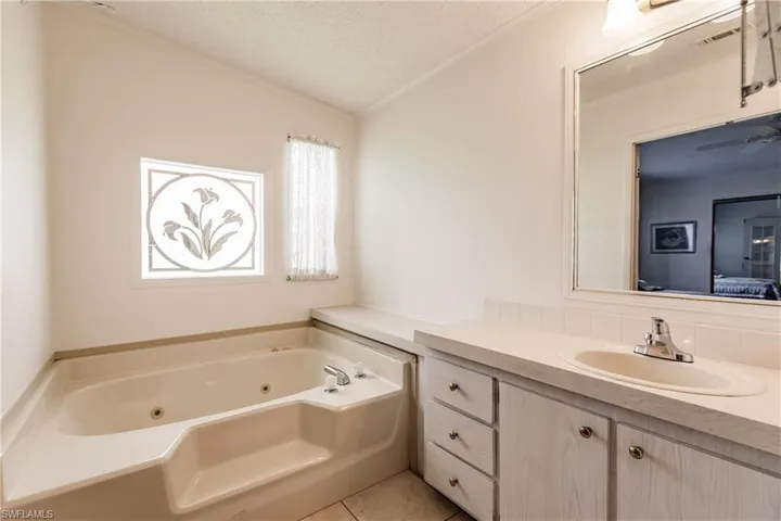Bathroom with a textured ceiling, vanity, a bathing tub, tile patterned flooring, and ornamental molding