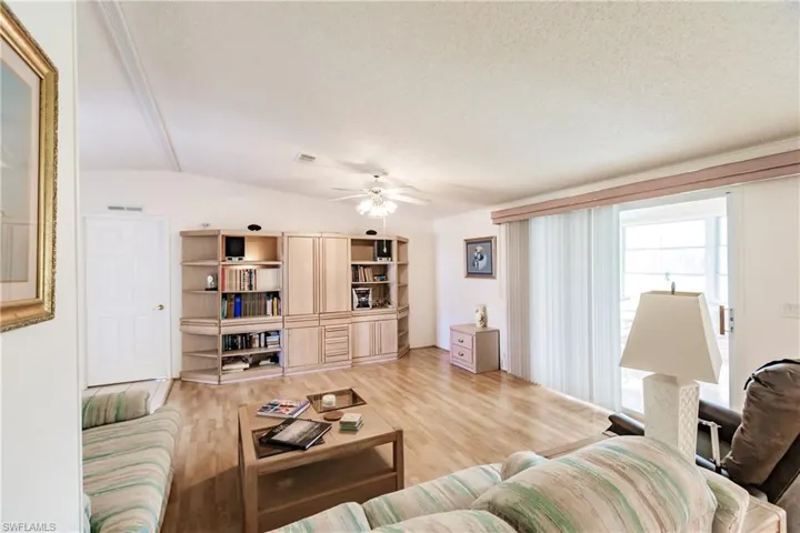 Living room featuring ceiling fan, light hardwood / wood-style floors, a textured ceiling, and vaulted ceiling