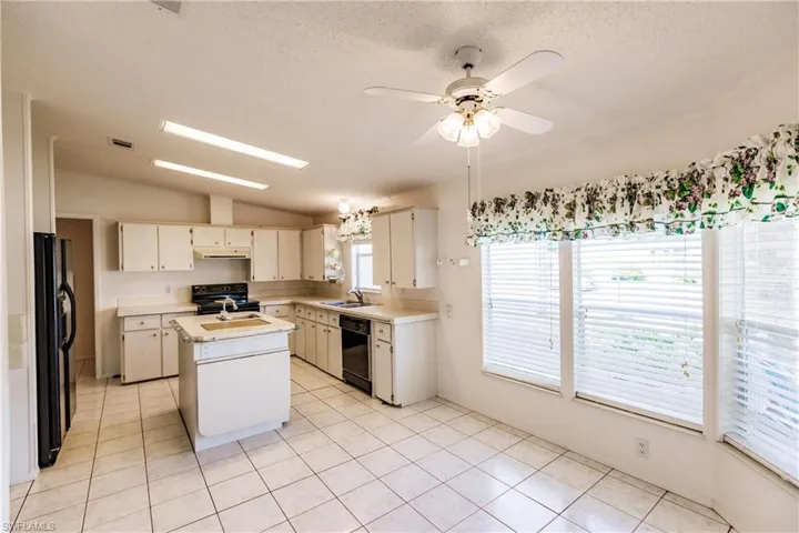 Kitchen with vaulted ceiling, a wealth of natural light, a center island, and ceiling fan