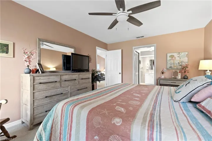 Carpeted bedroom with ensuite bath and a ceiling fan