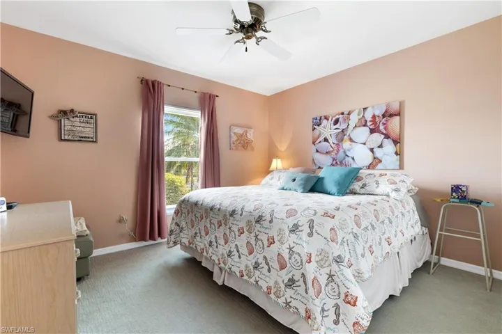 Carpeted bedroom with ceiling fan and baseboards