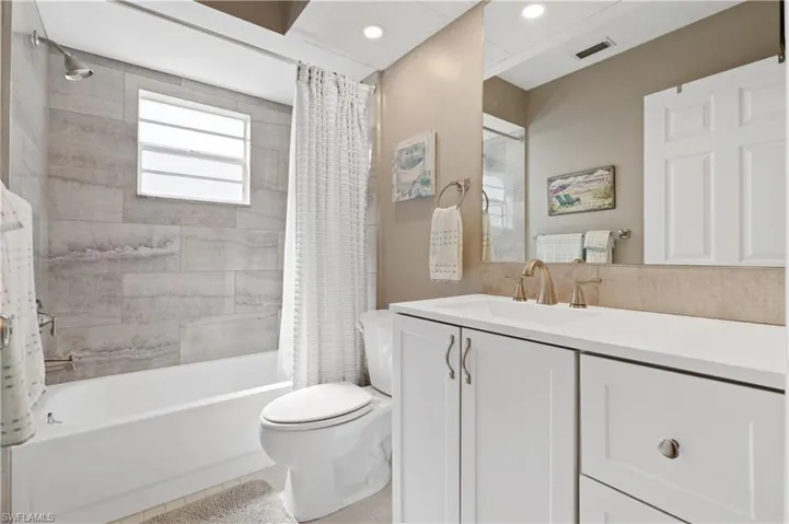 Bathroom featuring shower / bath combo with shower curtain, vanity, light tile patterned floors, and recessed lighting