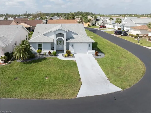 Ranch-style home with a shingled roof, a residential view, driveway, stucco siding, and a garage