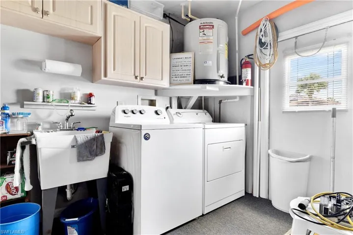 Laundry area featuring water heater, cabinet space, and washer and clothes dryer