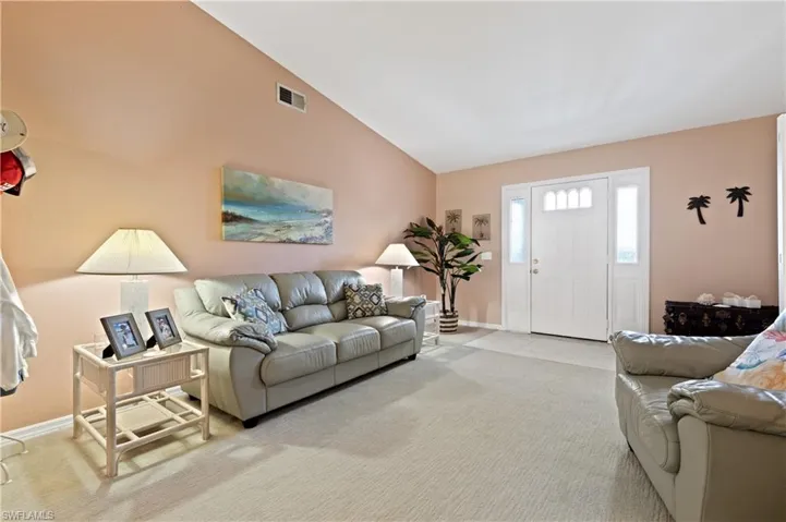 Tiled living area with vaulted ceiling and carpet