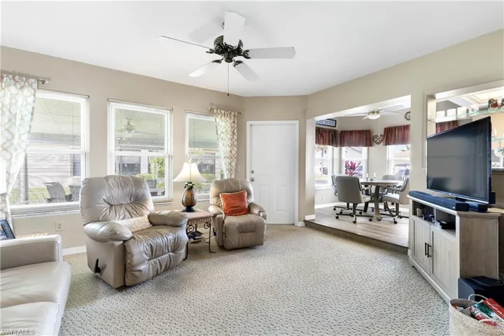 Living area with light colored carpet and a ceiling fan