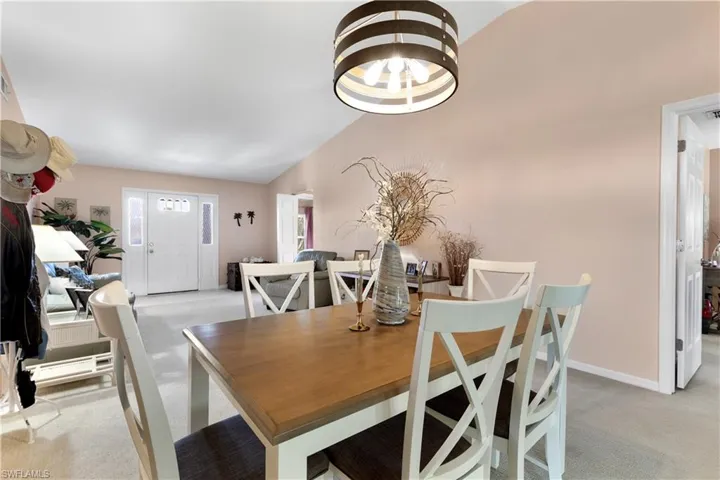 Dining room with light carpet, lofted ceiling, and a chandelier