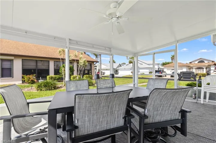 Sunroom with a residential view, ceiling fan, and outdoor dining space