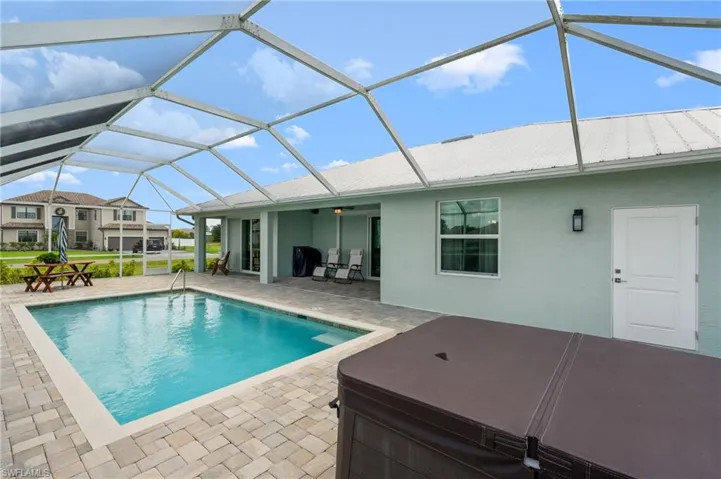 Swimming pool with a sunroom, a patio area, a hot tub, and glass enclosure