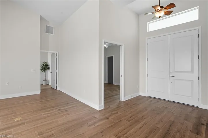 Entryway with high vaulted ceiling, ceiling fan, and wood finished floors