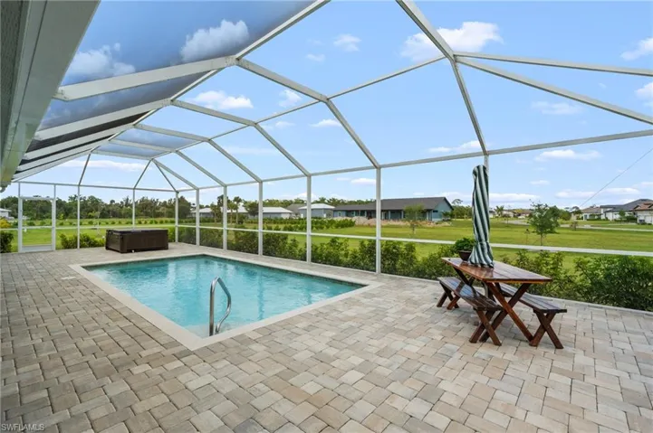 Outdoor pool featuring a hot tub, glass enclosure, a sunroom, and a patio area