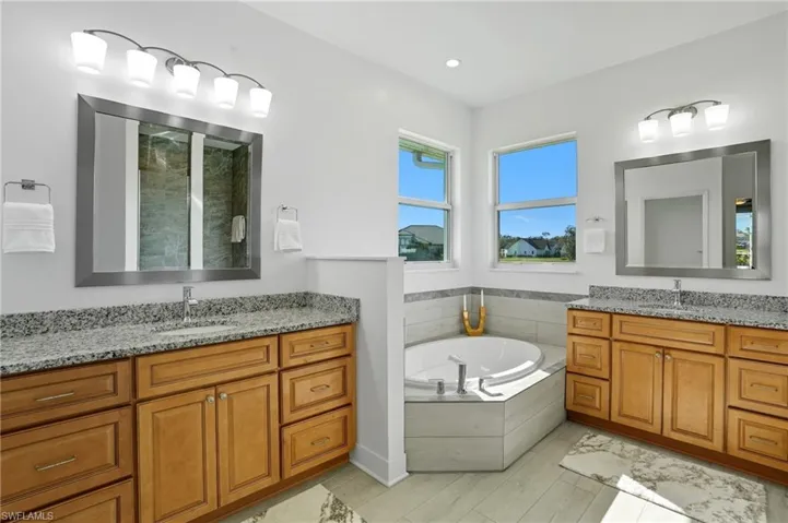 Full bath with two vanities, a garden tub, a stall shower, and recessed lighting