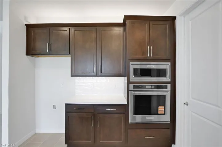 Kitchen with stainless steel appliances, dark wood finish cabinetry, and backsplash