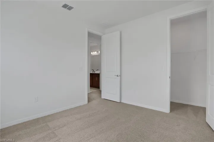 Unfurnished bedroom featuring light carpet and a spacious closet