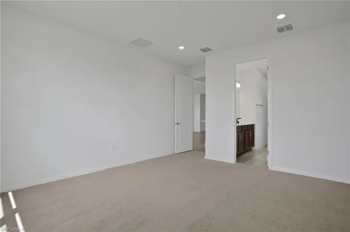 Unfurnished bedroom with light carpet, recessed lighting, and ensuite bathroom